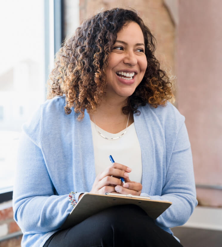 Woman chatting in group meeting holding notebook